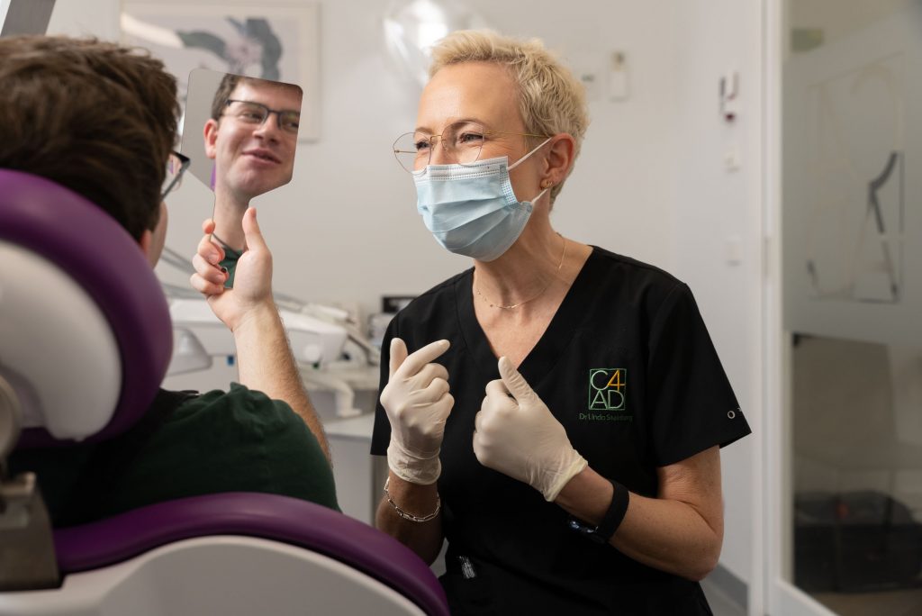 Dentist showing patient perfect teeth in mirror
